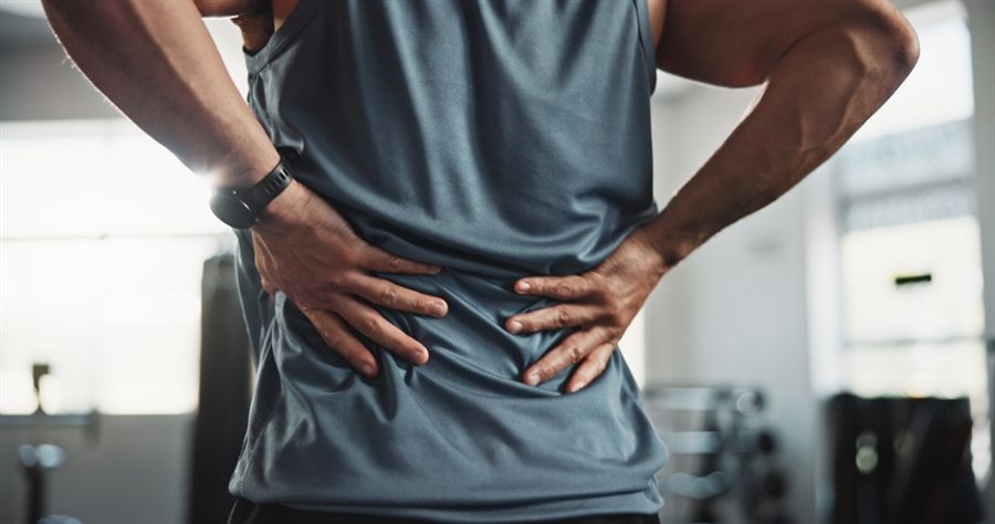 An active adult holding their lower back in pain at the gym